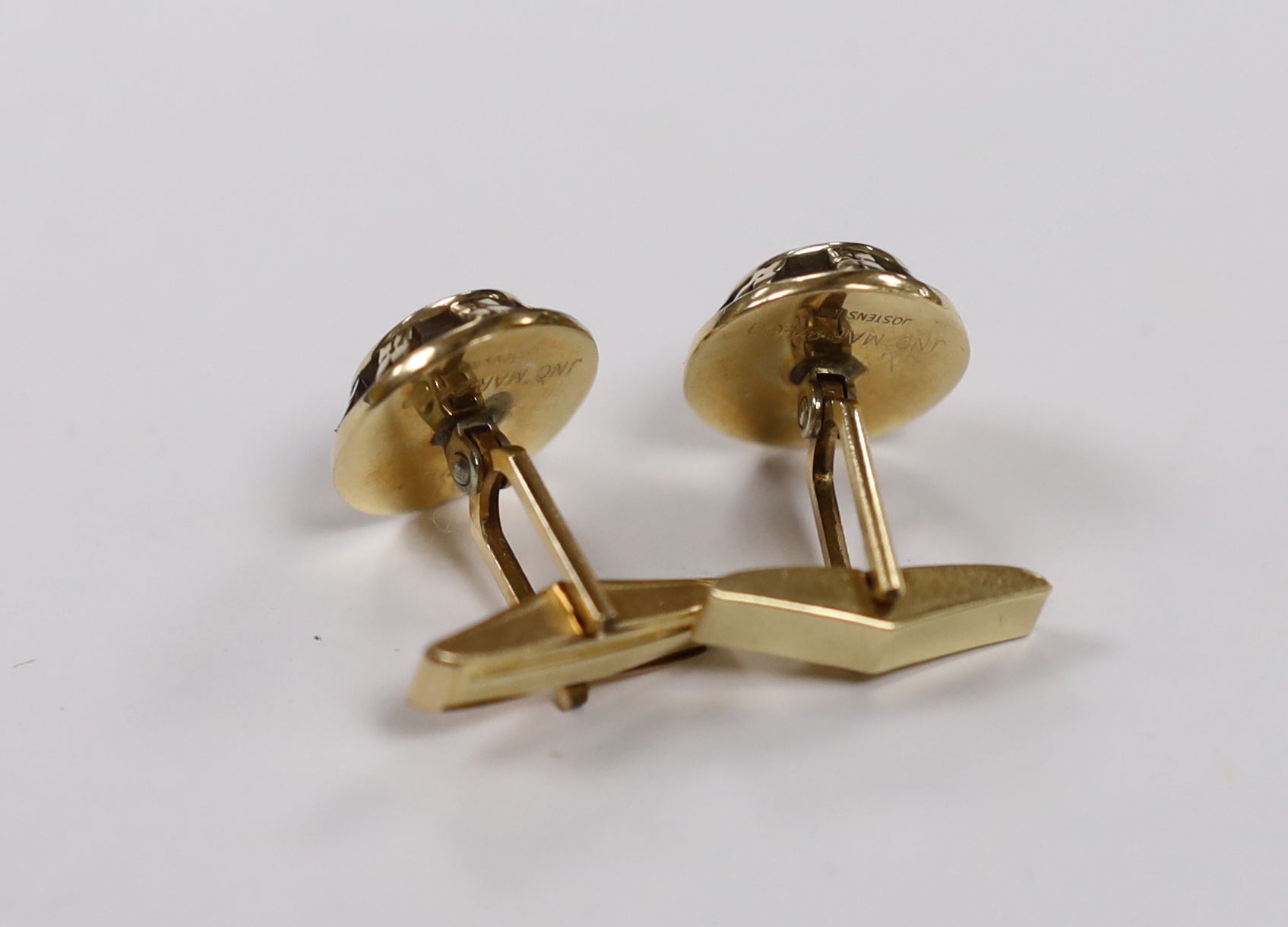 A pair of yellow metal and blue cabochon paste set cufflinks, the backs inscribed 'Jostens 10k', the swivelling arms inscribed '1/20 12k G.F.'.